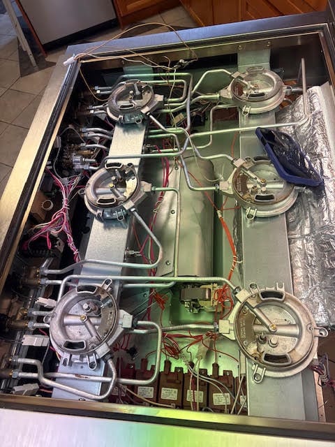 Opened stove showing the burners, wiring and components during a repair